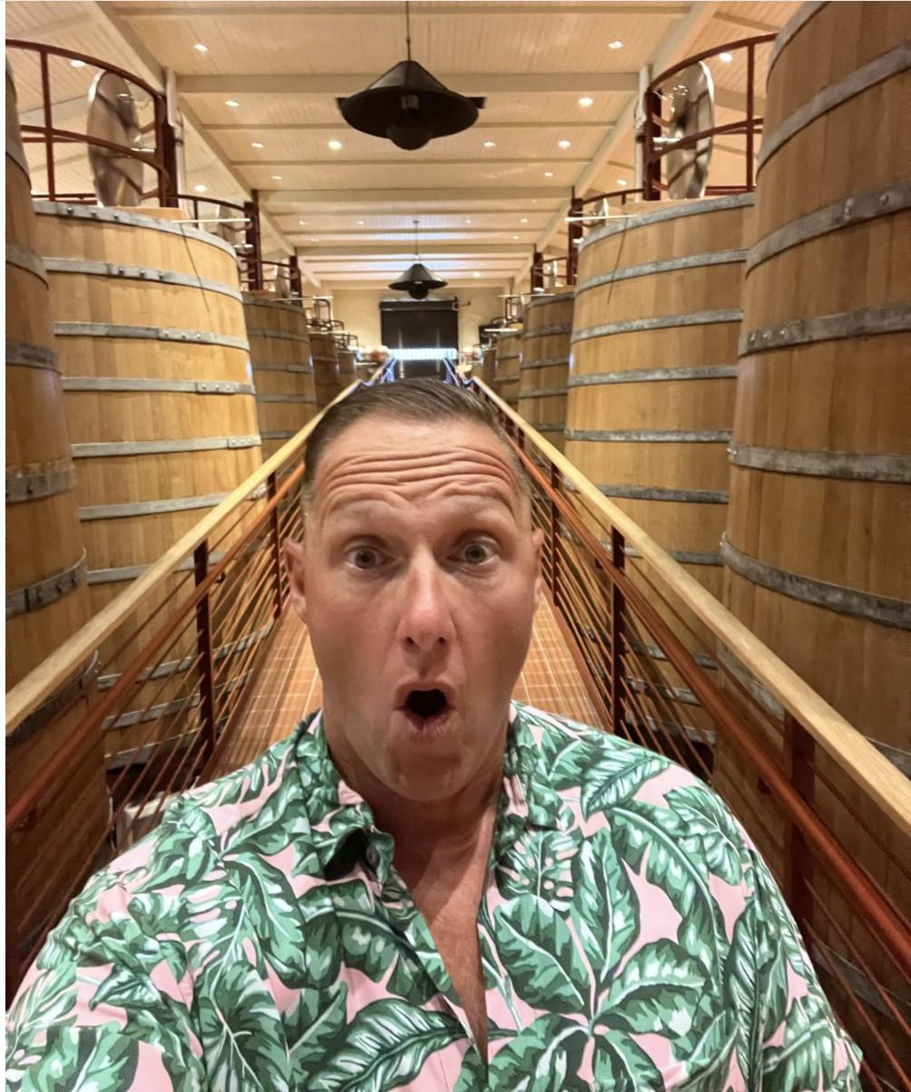 Wayne Partello takes a surprised selfie on a walkway between wine barrels at Robert Mondavi winery in Napa.