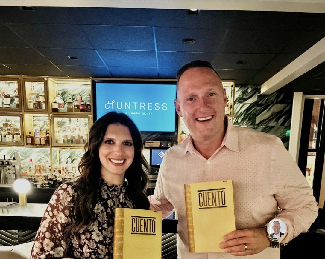 Wayne Partello and Katie Jackson smiling and holding CUENTO-branded notebooks.