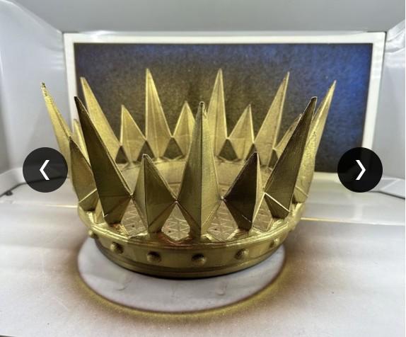 Gold-painted 3D-printed spiked crown prop on a workbench.