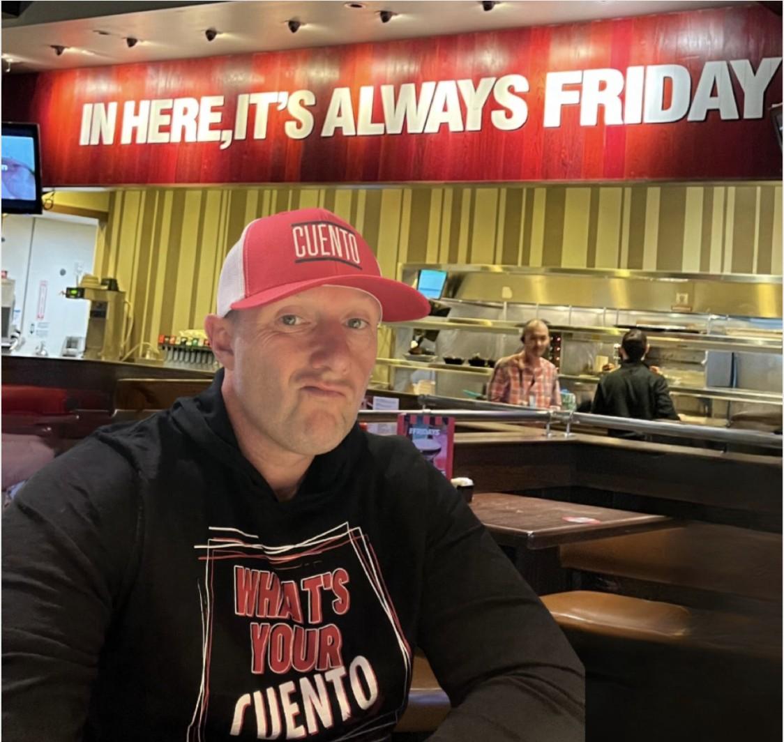 Wayne Partello takes a selfie at TGI Fridays wearing a CUENTO cap and "What's Your CUENTO" shirt.
