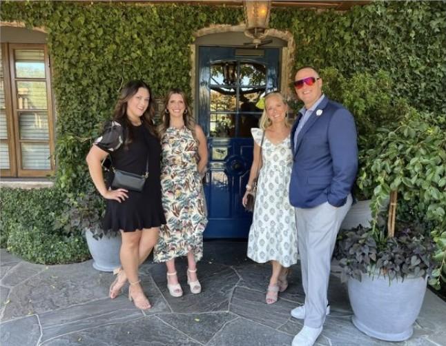 Wayne and three friends posing in front of a blue door surrounded by greenery.