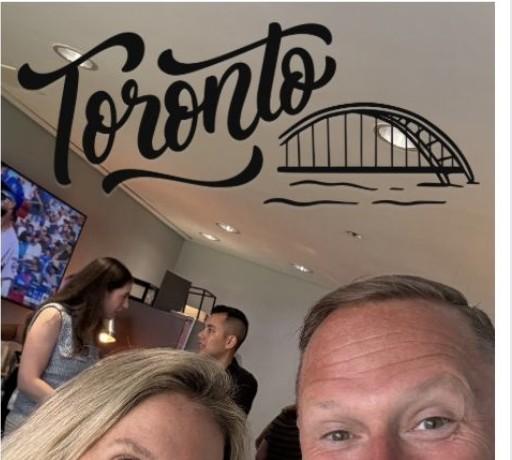 Wayne Partello taking a selfie with a colleague under a 'Toronto' wall decal