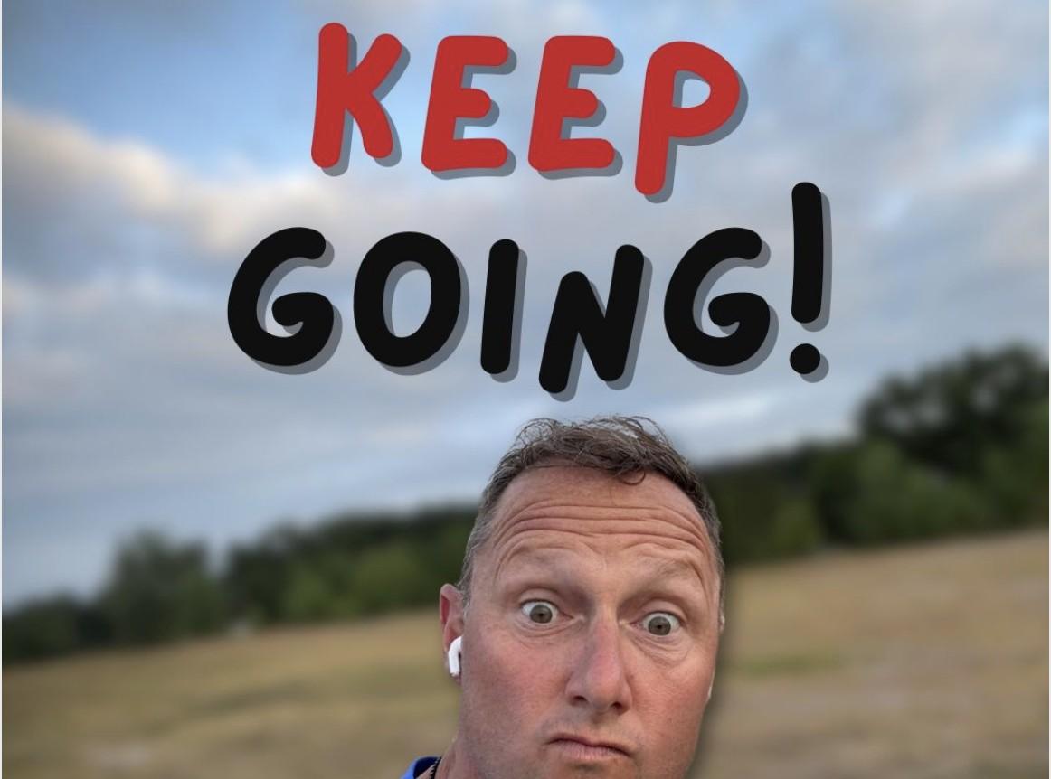 Wayne Partello taking a selfie in a field at dusk wearing an earbud, captioned 'Keep Going!'